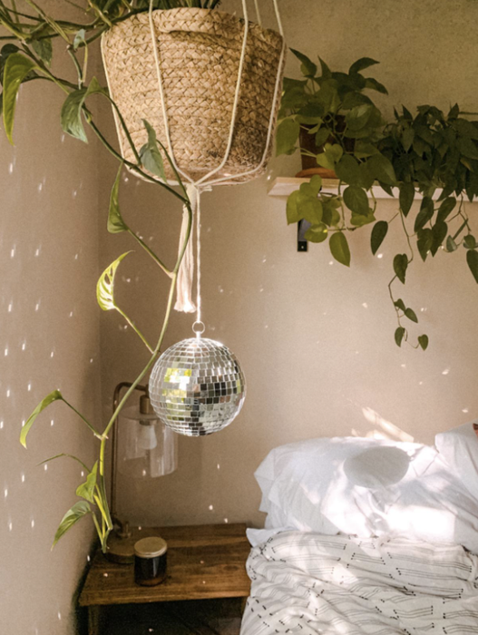 A reviewer's bedroom with a disco ball suspended from a plant, casting playful light across the room.