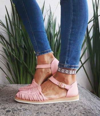 A model pairs pink Huarache sandals with jeans for a stylish look.