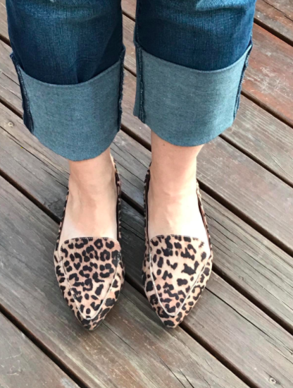 The reviewer is seen wearing cheetah-print loafers with cuffed light blue denim jeans.
