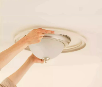 A person's hand installing a ceiling light fixture