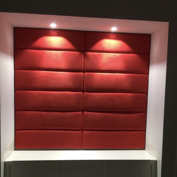 Red headboards positioned on a wall, illuminated by soft lighting.