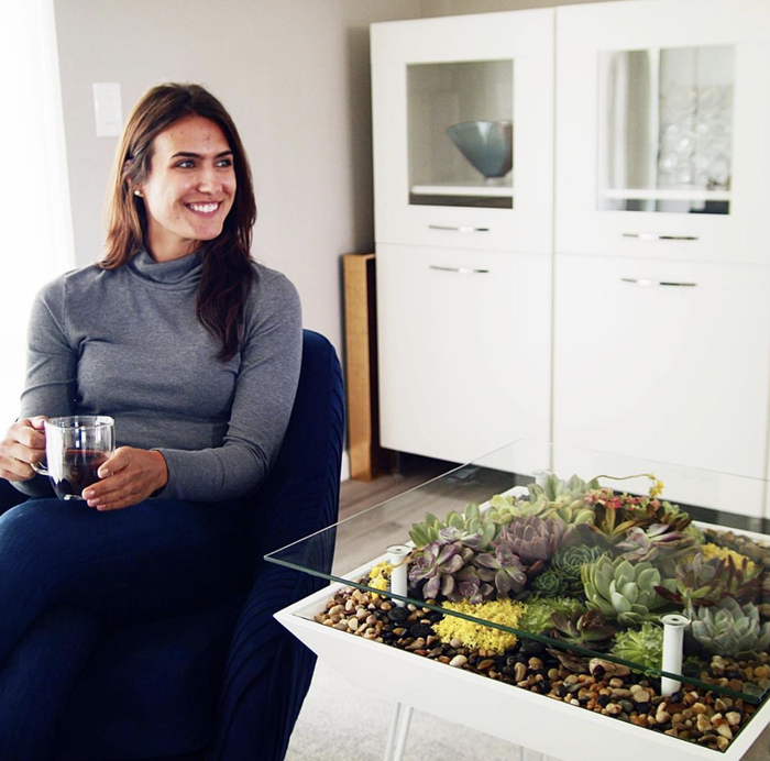 A person smiling while standing beside the table.