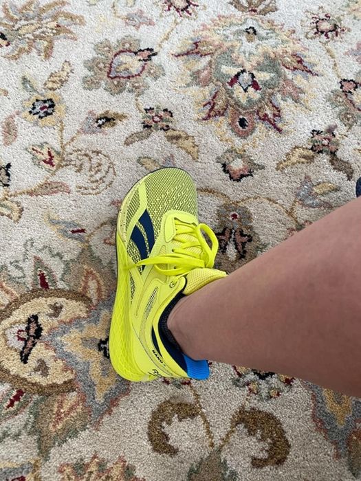 A reviewer shows off neon yellow cross-training sneakers.