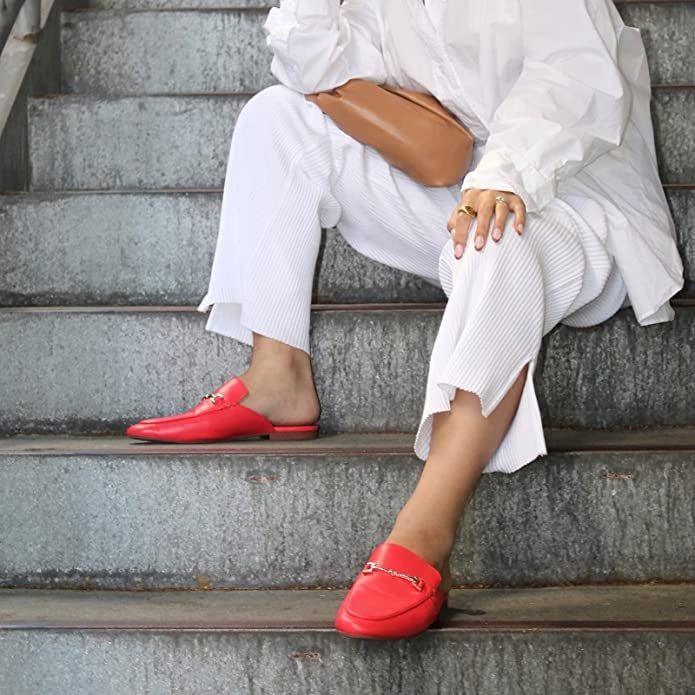 Model showcases bright red mules featuring gold accents on the front
