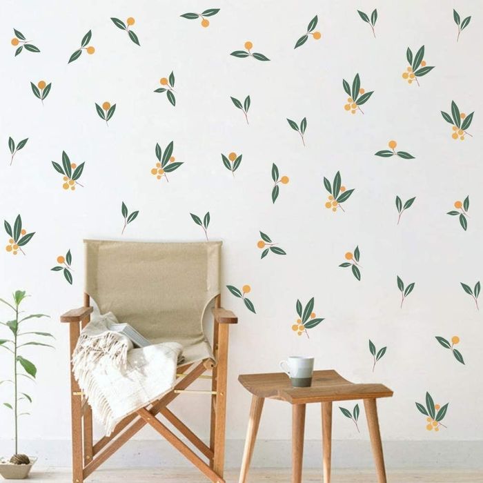 A white wall adorned with several tangerine leaf stickers, adding a pop of color and personality.