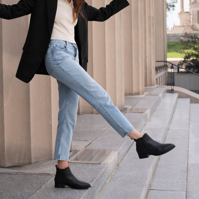 A person dressed in a black blazer and jeans, highlighting stylish ankle boots — ideal for a footwear feature article.