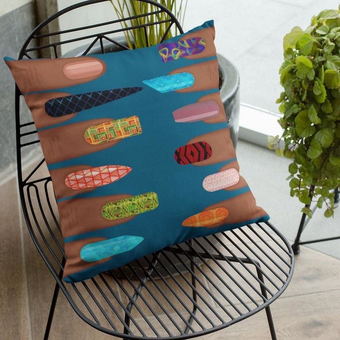 A square throw pillow with fingers on each side, each sporting a different manicured fingernail.