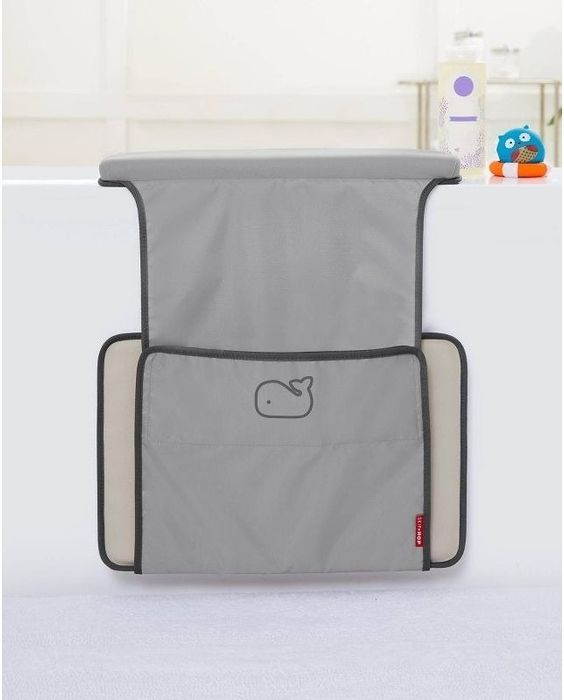 A gray bath kneeler featuring a cartoon whale design, paired with an elbow rest, placed on a bathtub with a blue rubber duck and lotion bottle in the background