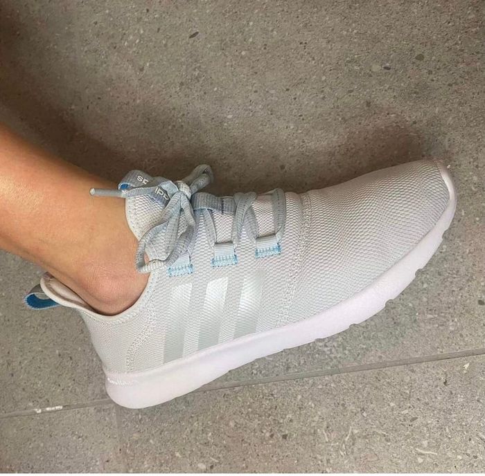A person seen from above, wearing a white sneaker with light blue details.