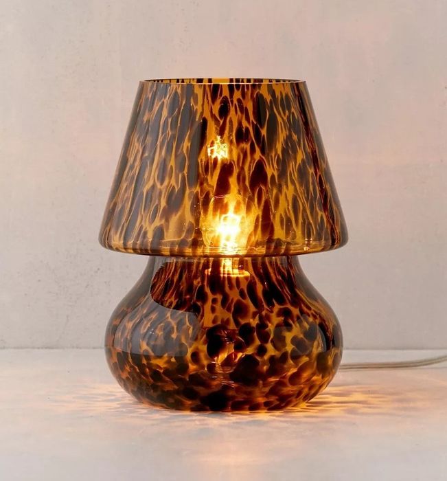 A bulbous glass lamp with an attached shade, featuring a tortoise shell pattern that adds elegance to any space.