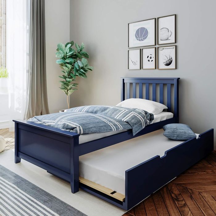 A chic bedroom featuring a navy blue bedframe with an integrated pull-out trundle, surrounded by decorative pillows and basketball-themed wall art.