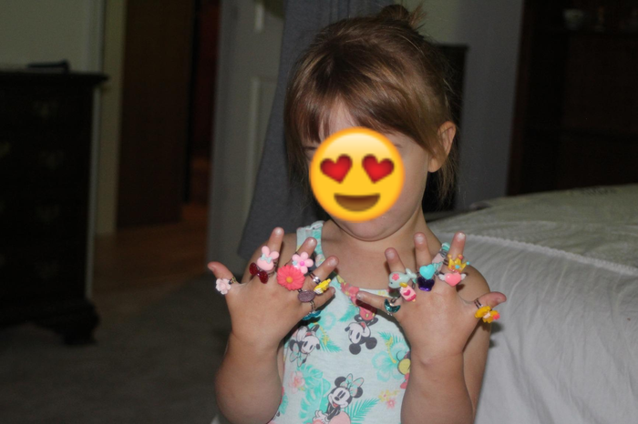 A reviewer's photo showing a child wearing all 24 rings on their fingers