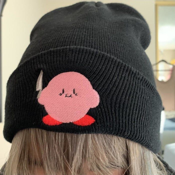A black beanie featuring a patch of Kirby holding a knife.