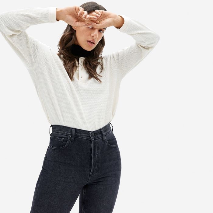The model is dressed in a long-sleeve white shirt with a three-button collar.