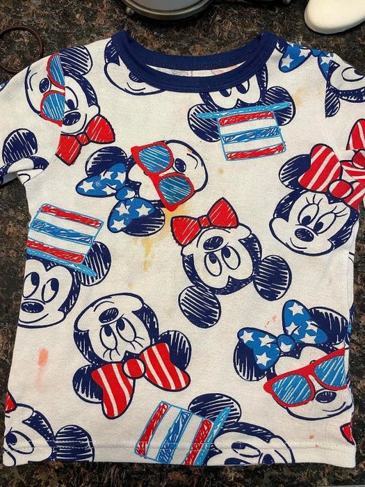 Reviewer's photo of a child’s t-shirt stained with a Mickey and Minnie Mouse pattern, captured before using the Emergency Stain Rescue products