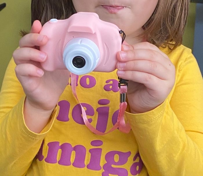 A reviewer's photo of a child holding the pink toy camera