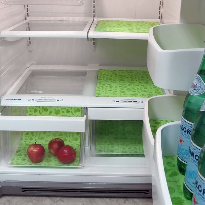 open refrigerator door showcasing green liners on the shelves and four glass sections