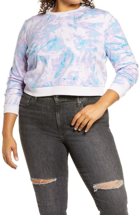 Model rocking a cropped tie-dye sweatshirt paired with jeans