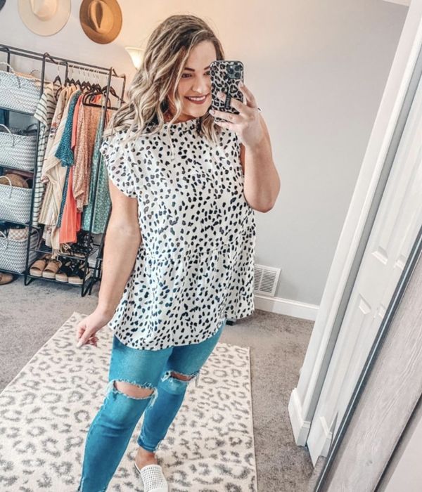 Person wearing a white and black dotted tunic paired with denim jeans
