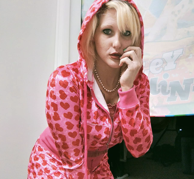 A reviewer is seen wearing a zip-up hoodie adorned with red hearts all over.