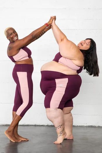 Models exchanging a high-five while dressed in a stylish pink and burgundy shorts set.