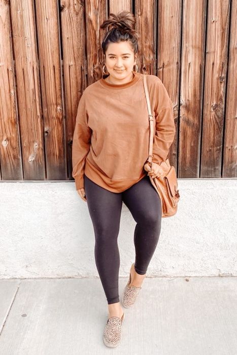 reviewer wearing the sweatshirt in brown, paired with leggings.