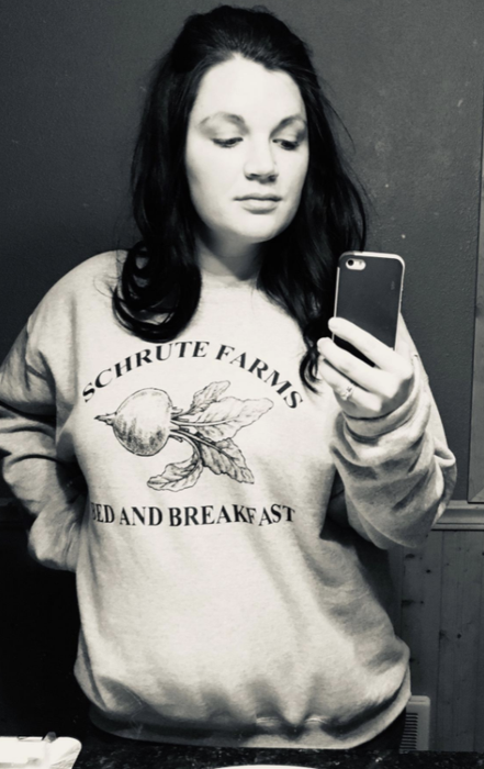 A reviewer sports a sweatshirt from The Office featuring the Schrute Farms Bed and Breakfast logo.