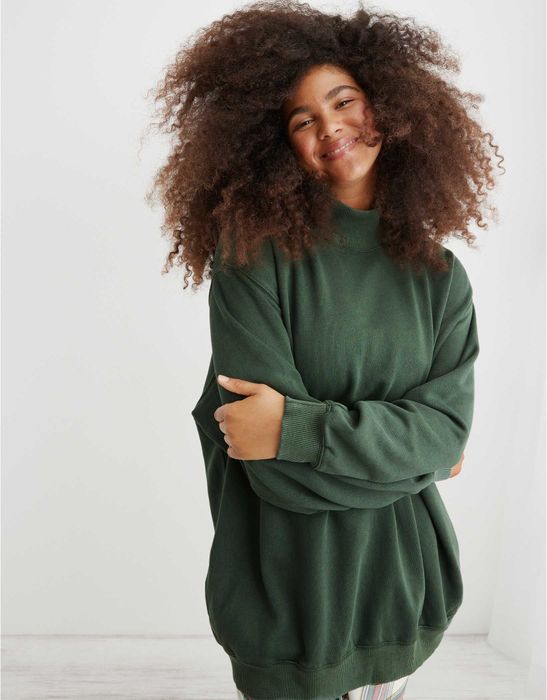 A model is seen wearing the smock neck sweatshirt in forest green.