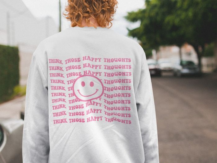 A sweatshirt featuring a smiley face and the design 'think those happy thoughts' on the back.
