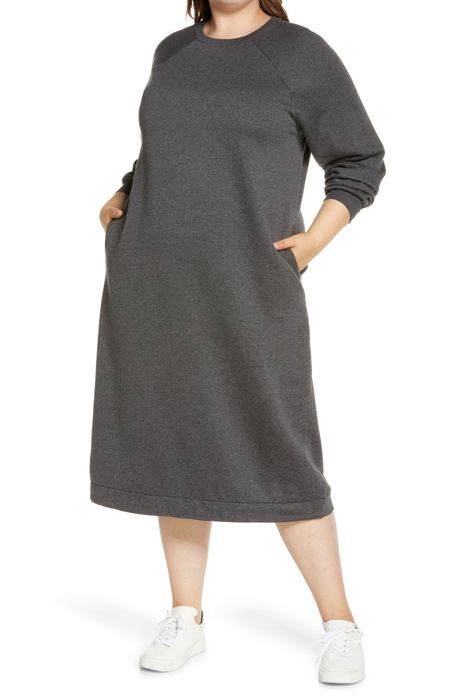 A model is showcasing a roomy midi sweatshirt dress that offers plenty of space for comfort.