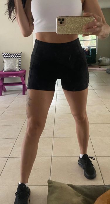 A reviewer capturing a selfie while wearing sleek black biker shorts.
