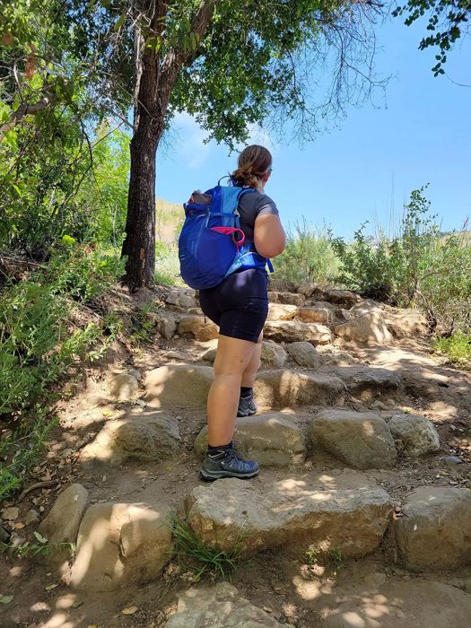 A reviewer trekking up a rocky slope while wearing the black shorts.