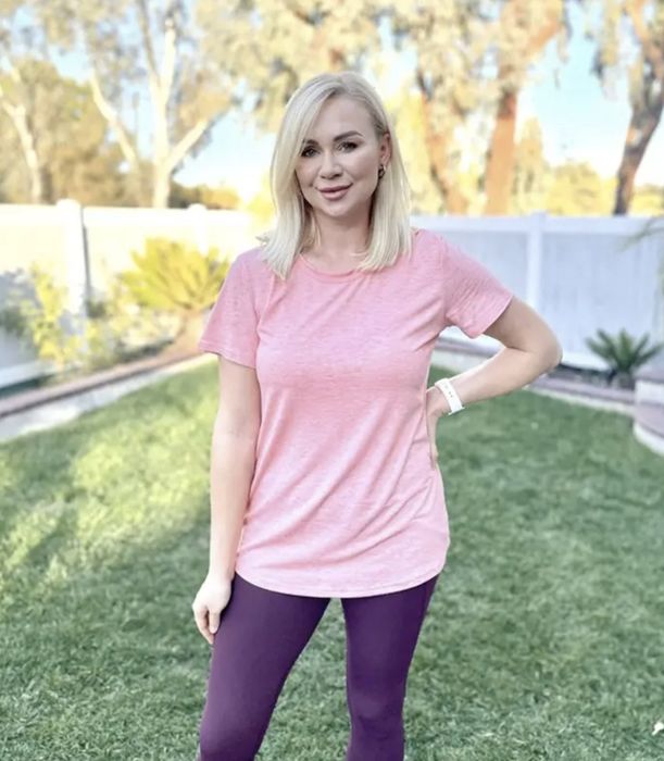 A person wearing a pink T-shirt paired with purple leggings.
