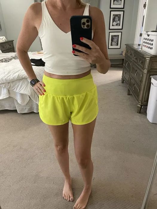 A reviewer sporting vibrant yellow running shorts paired with a white tank top.