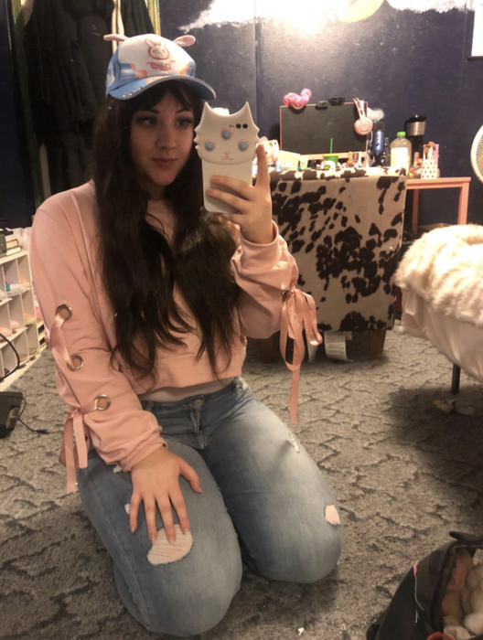 A reviewer styles a pair of jeans with a sweatshirt featuring lace-up detailing on the sleeves.