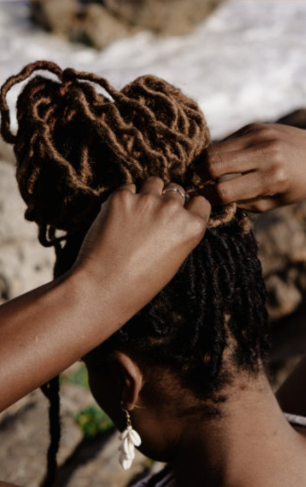 A model using a hair tie to secure locs into a bun.