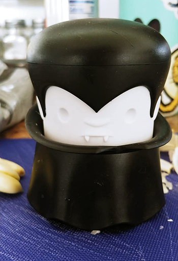 The garlic crusher resting on a countertop.