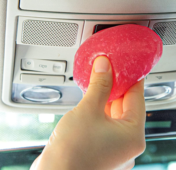 A model cleaning car surfaces with gel to remove dust.