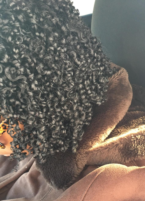A reviewer with coily hair that looks shiny and beautifully defined