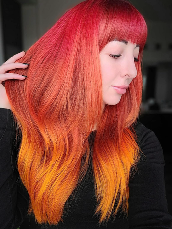 The reviewer proudly shows off their stunning red and orange ombre hair.