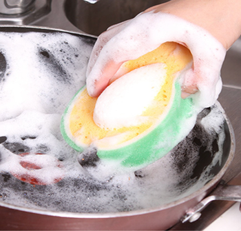 A model cleaning a pan with a soapy, avocado-shaped sponge.