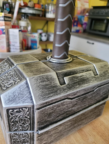 A replica of Thor's mighty hammer, Mjolnir, rising from a patterned box on a counter.