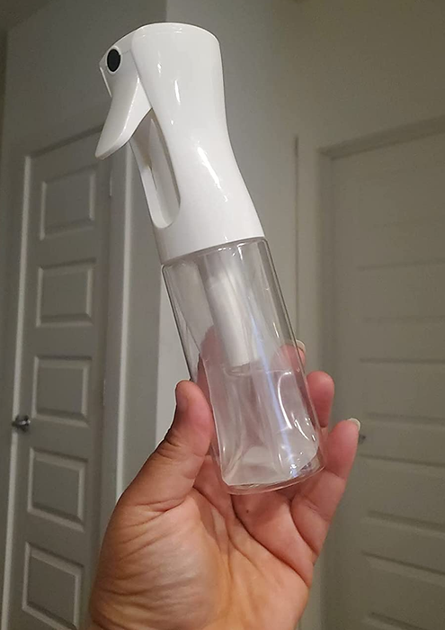 A reviewer holding a spray bottle filled with water.