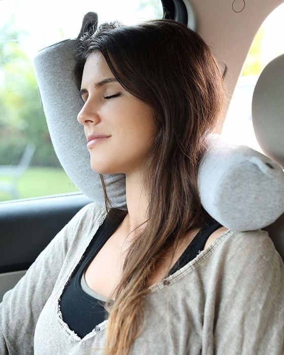A model resting against a car door, thanks to the flexible travel pillow.
