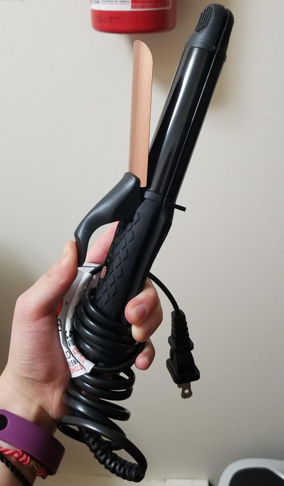 a reviewer holding the 2-in-1 hair styling tool