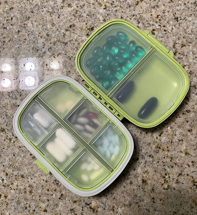 A reviewer's photo showing the green pill organizer filled with a variety of pills.