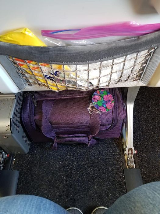 The suitcase stored beneath the seat of an airplane.