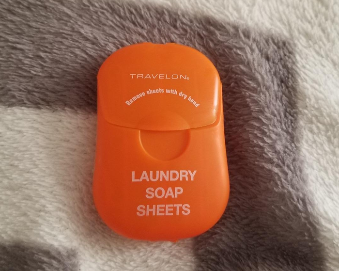 reviewer photo featuring the orange pack of laundry soap sheets placed on top of a blanket