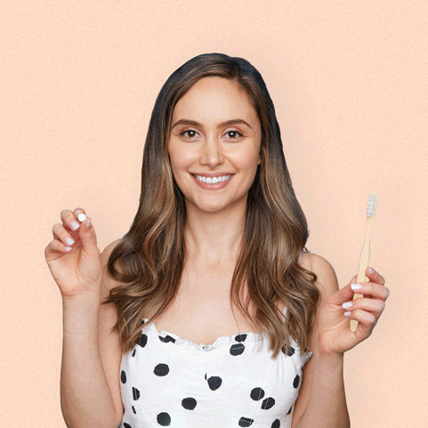 A gif of a model placing a white tablet in their mouth and beginning to brush their teeth