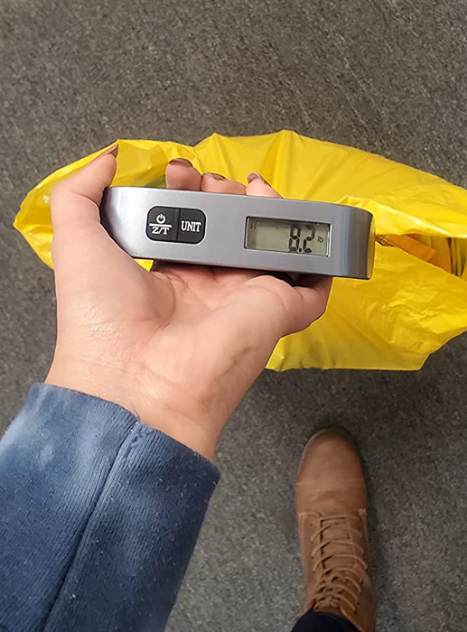 a reviewer using the digital luggage scale to measure the weight of a small bag